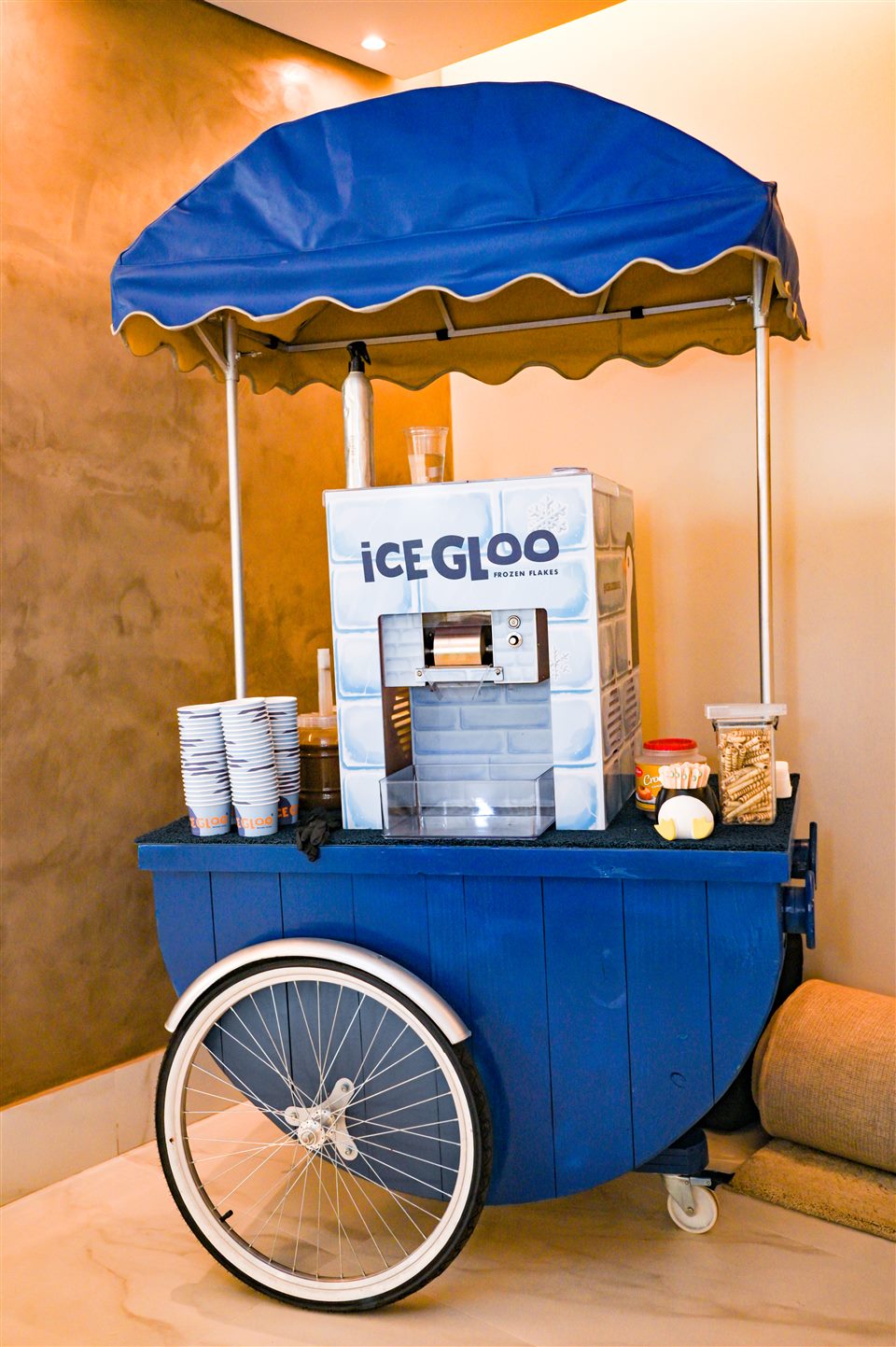 Carrinho azul IceGloo com cobertura e equipamento de preparo em um evento